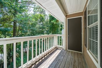 A wooden balcony overlooking a trees.